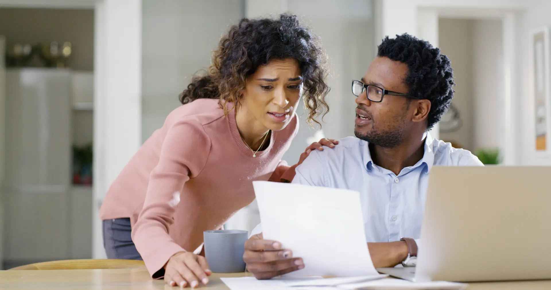Frustrated, interracial couple and documents with laptop or eviction notice for financial crisis, bills or expenses. Worried, man and woman with paper or computer for missed payment, mortgage or tax