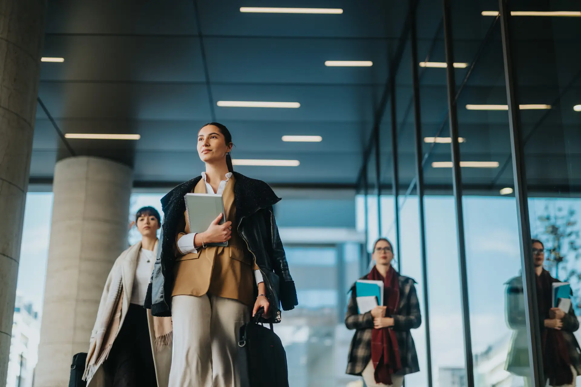 Confident businesswomen walking together in an urban environment carrying documents