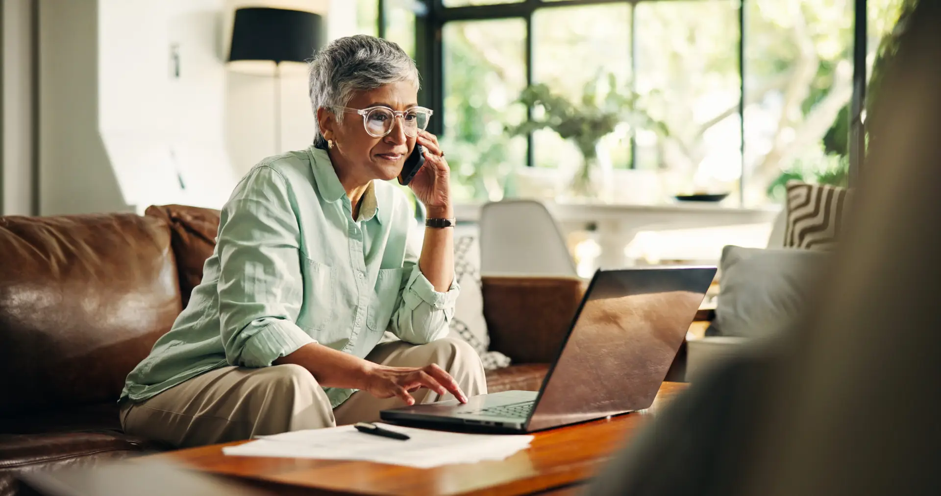 Budget, finance or senior woman with phone call by laptop for annuity fund, tax planning or banking. Wealth, old person and talking to consultant in home for retirement savings account or bills query