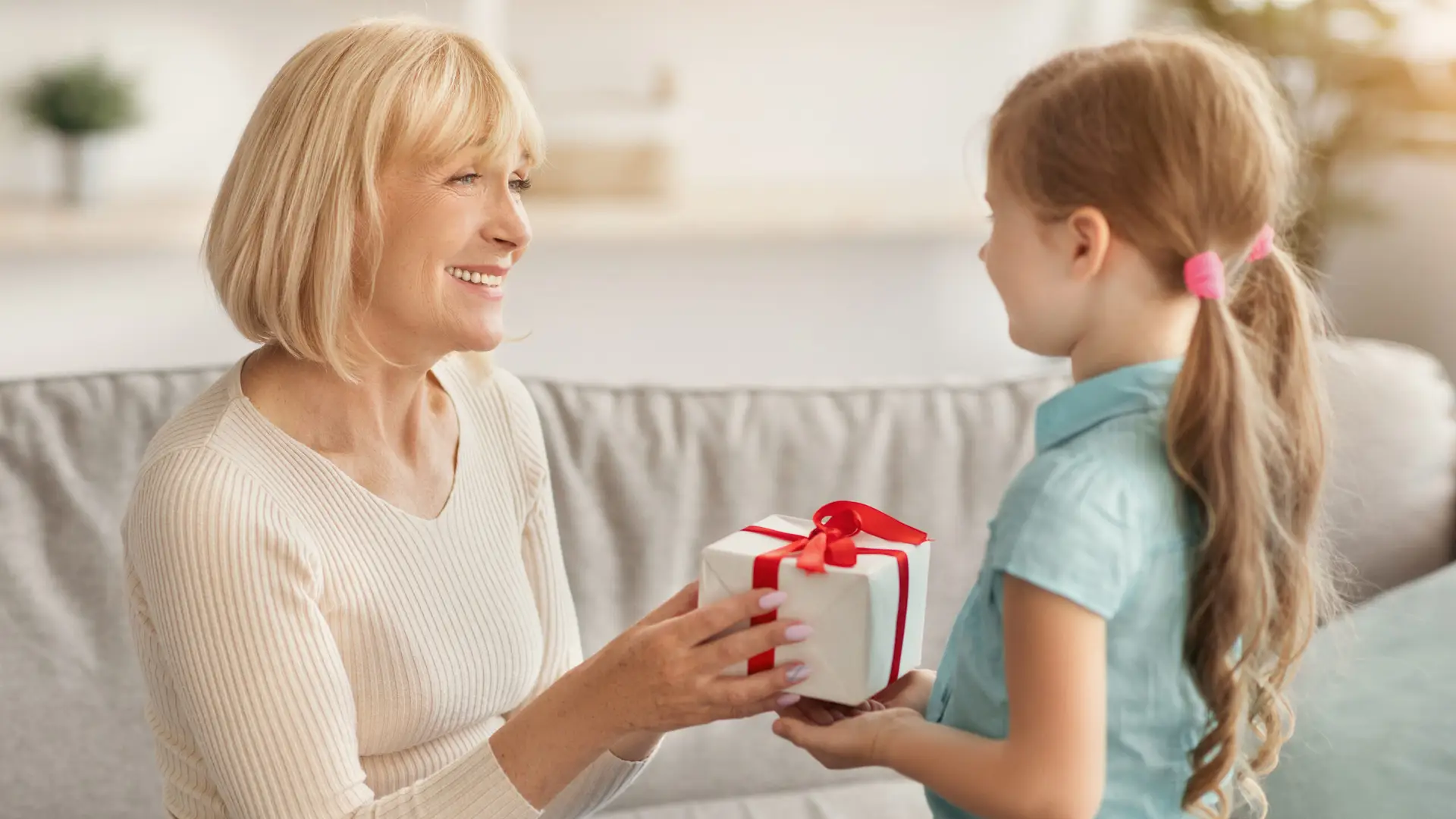 Little girl celebrating granny's day, greeting lady with box