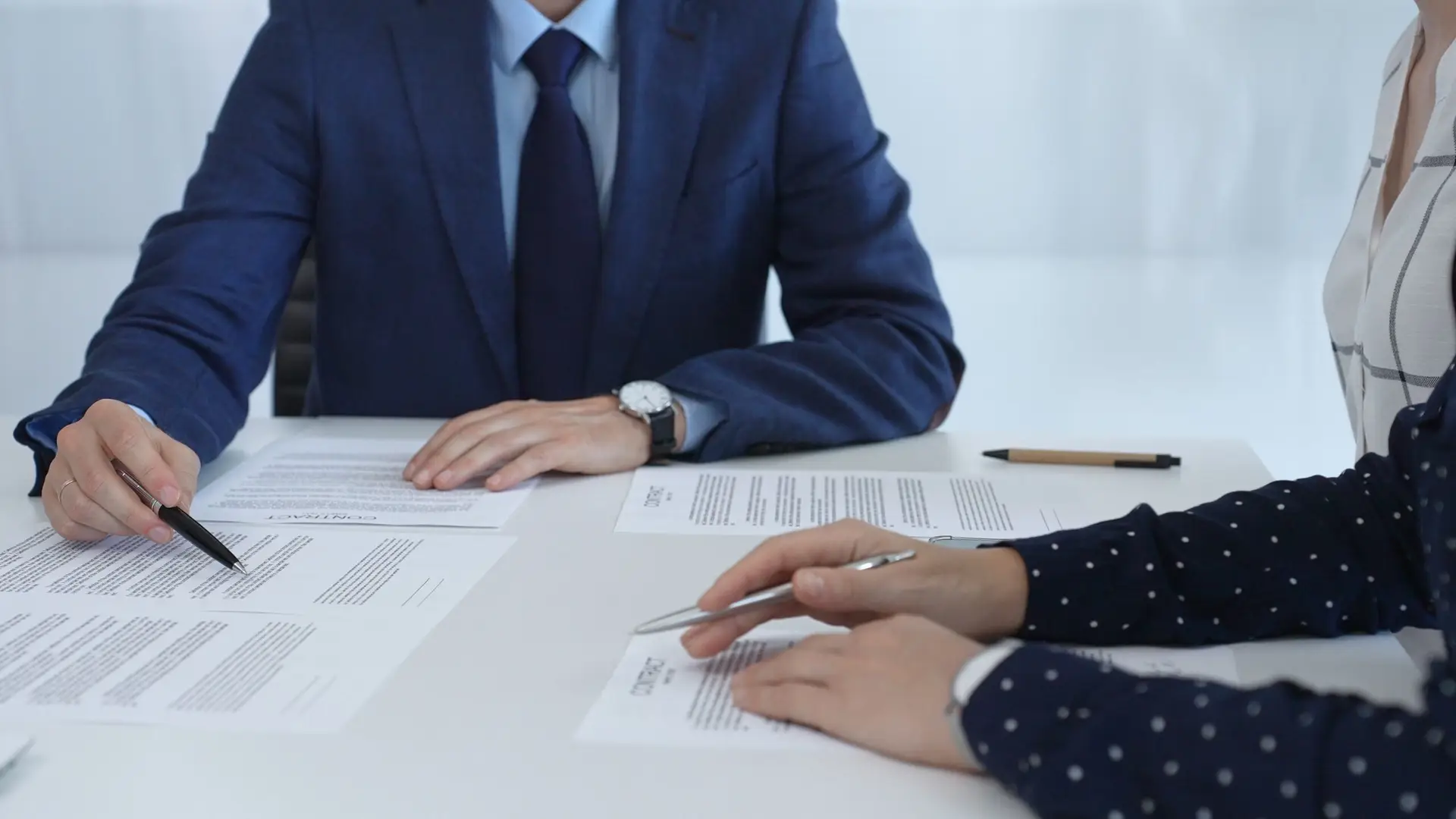 Business people reviewing contract during a meeting, pointing at specific clauses and discussing potential amendments before signing the agreement