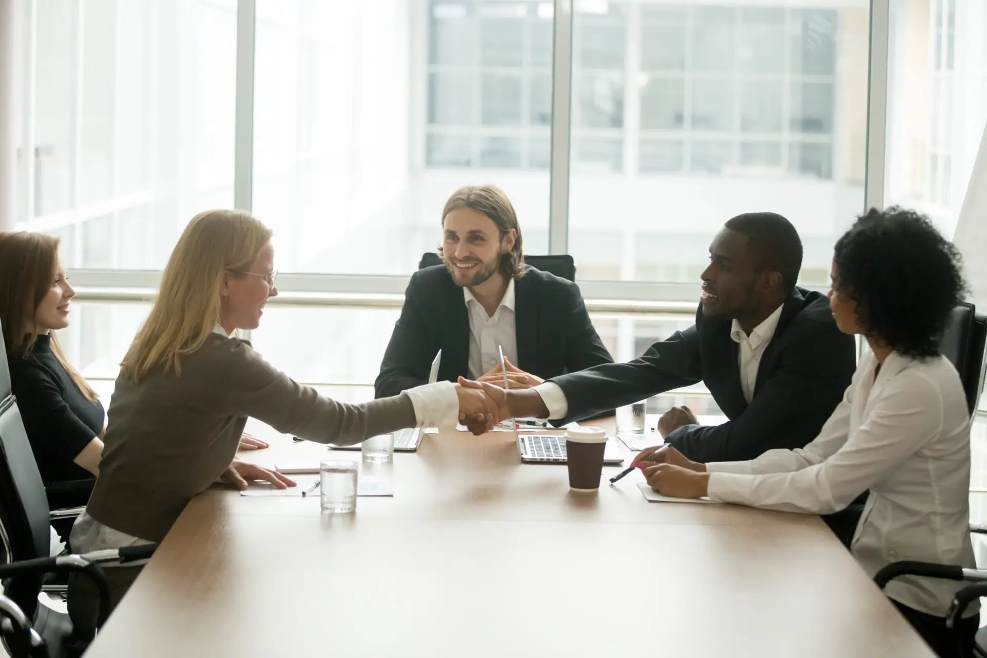African businessman and caucasian businesswoman shaking hands ov
