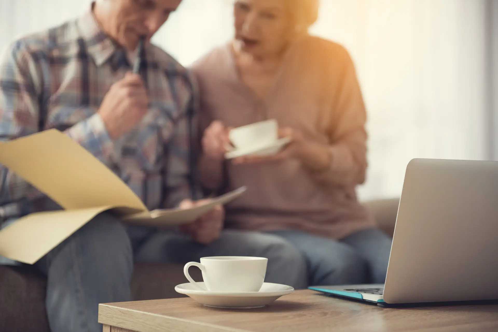 Cup and notebook on desk near senior pensioners
