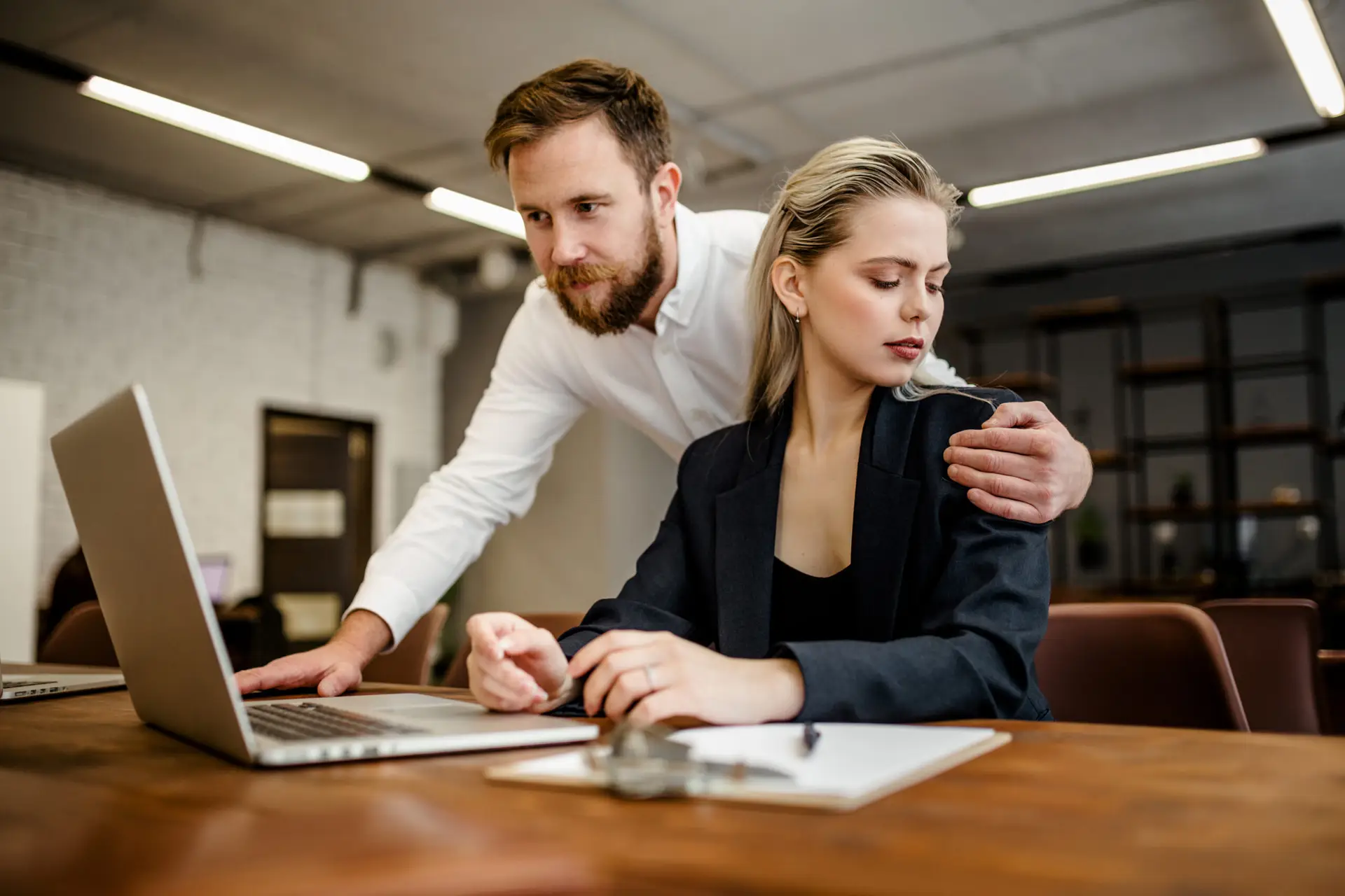A bearded male Manager harasses his colleague a girl who works a