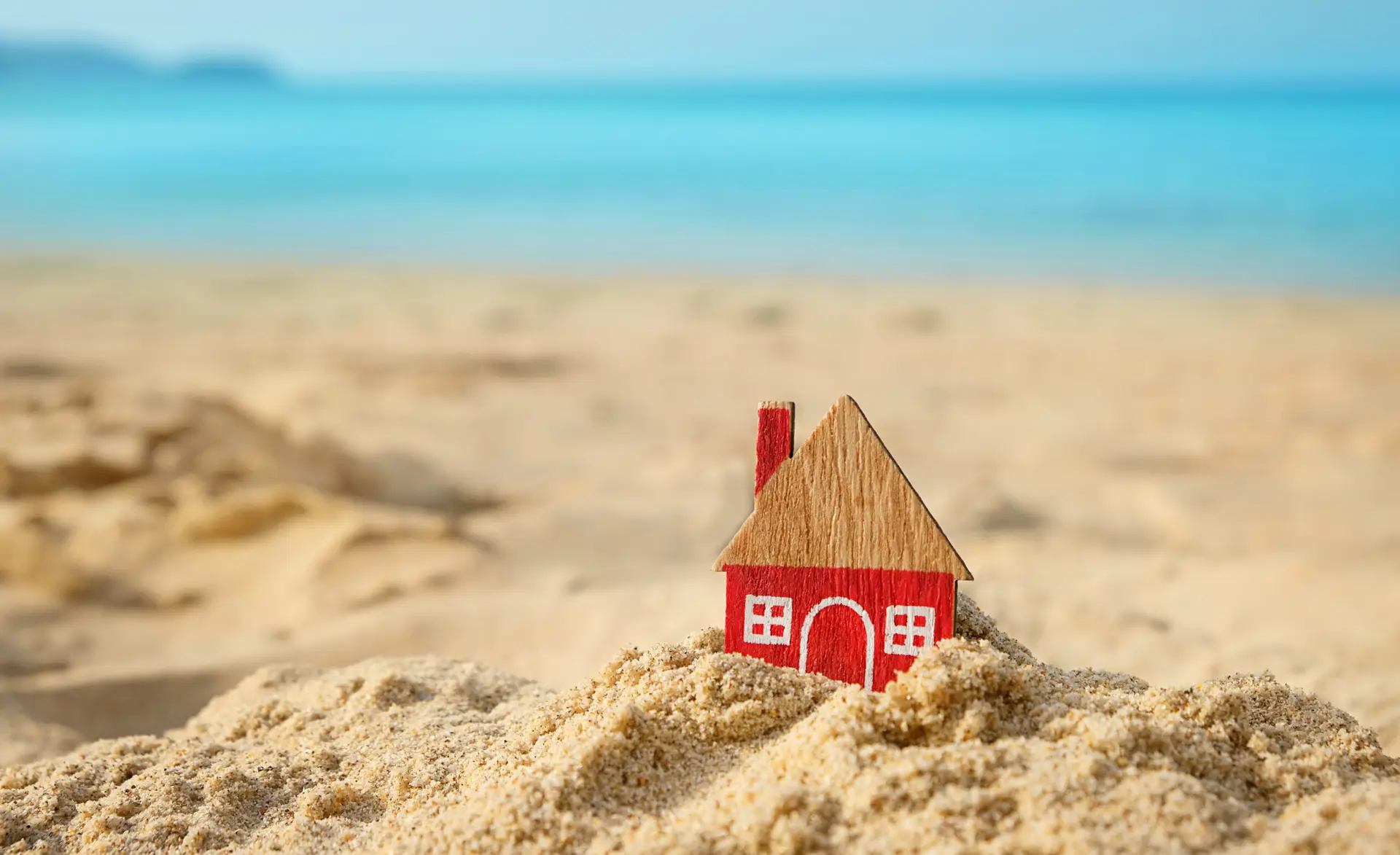 little red house on sand beach, tropical natural background. Home, symbol of love, family. Concept of protecting home, Mortgage, Real estate. Eco Friendly House