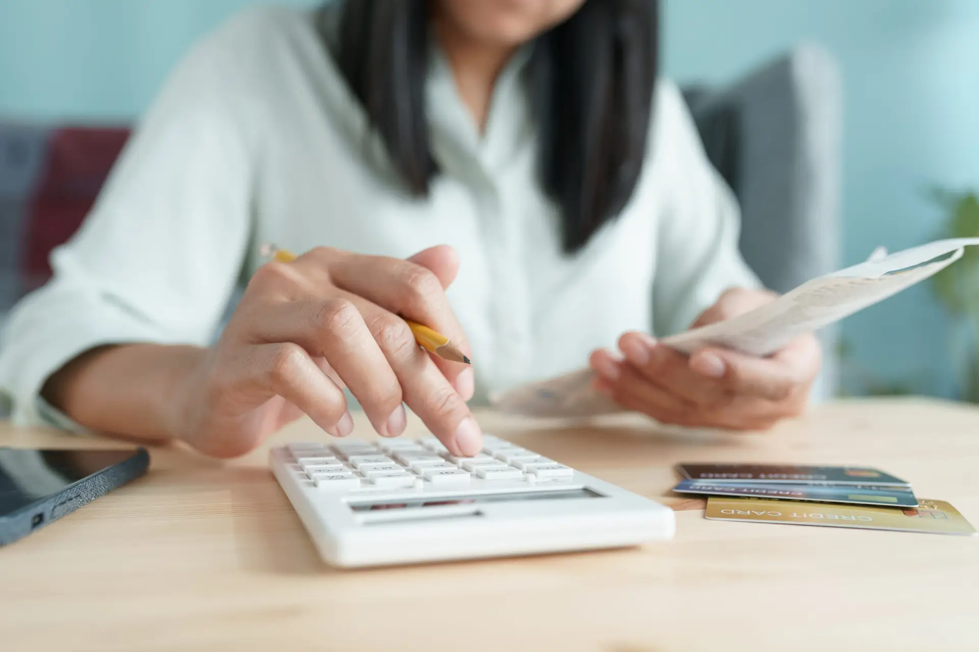 Hand of Asian girl are calculate monthly expenses and credit card at home