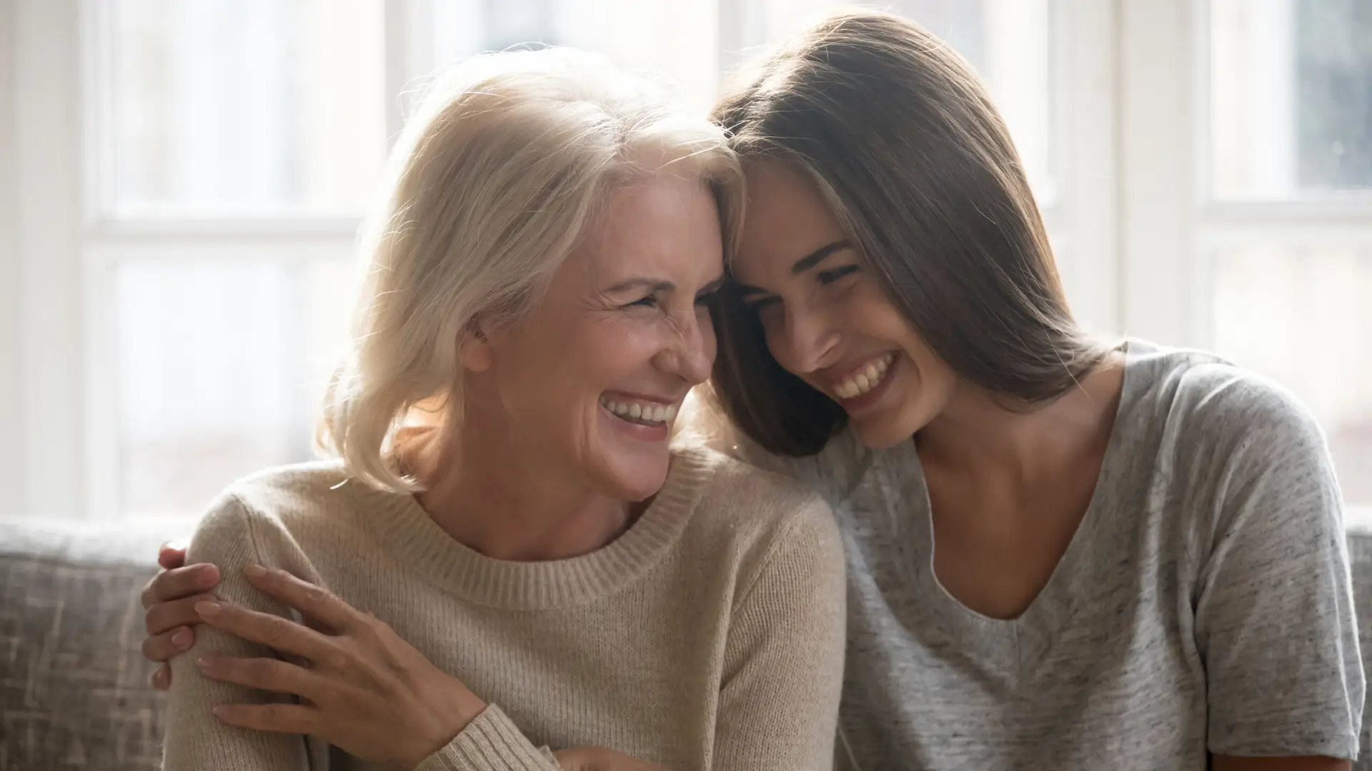 Smiling grownup daughter and elderly mom have fun laughing