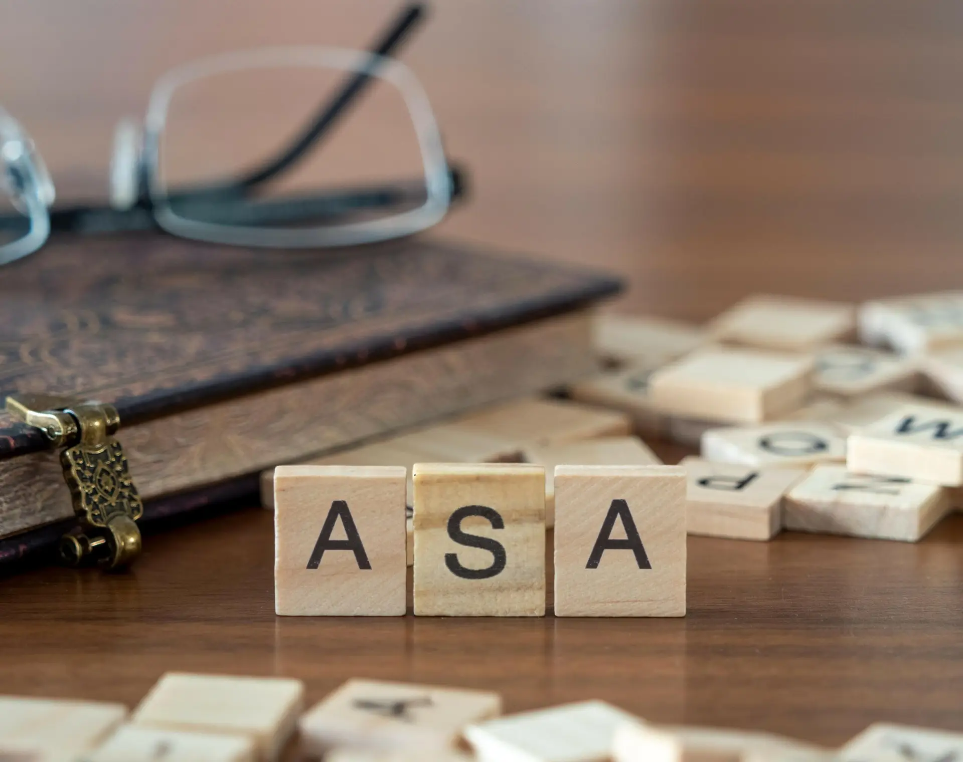 the acronym asa for advertising standards authority word or concept represented by wooden letter tiles on a wooden table with glasses and a book