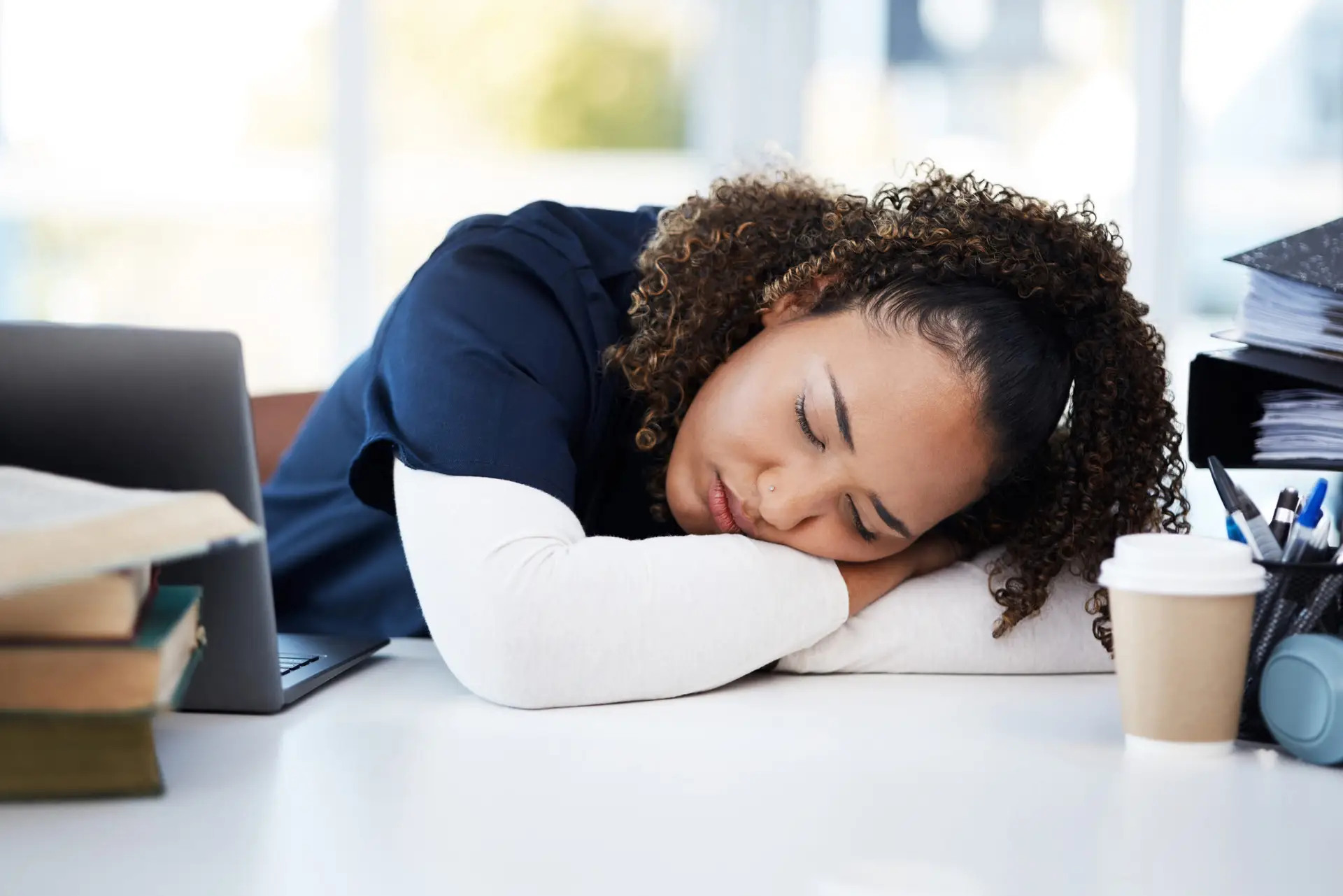 Woman, technology or sleeping medical student in tired, research books burnout or hospital learning fatigue. Stress, exhausted or asleep healthcare nurse by laptop in scholarship medicine internship