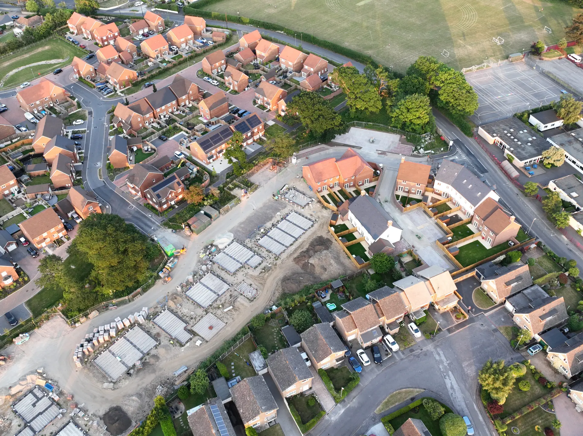 Aerial view looking on an area of new build housing construction on the edge of existing houses and green fields