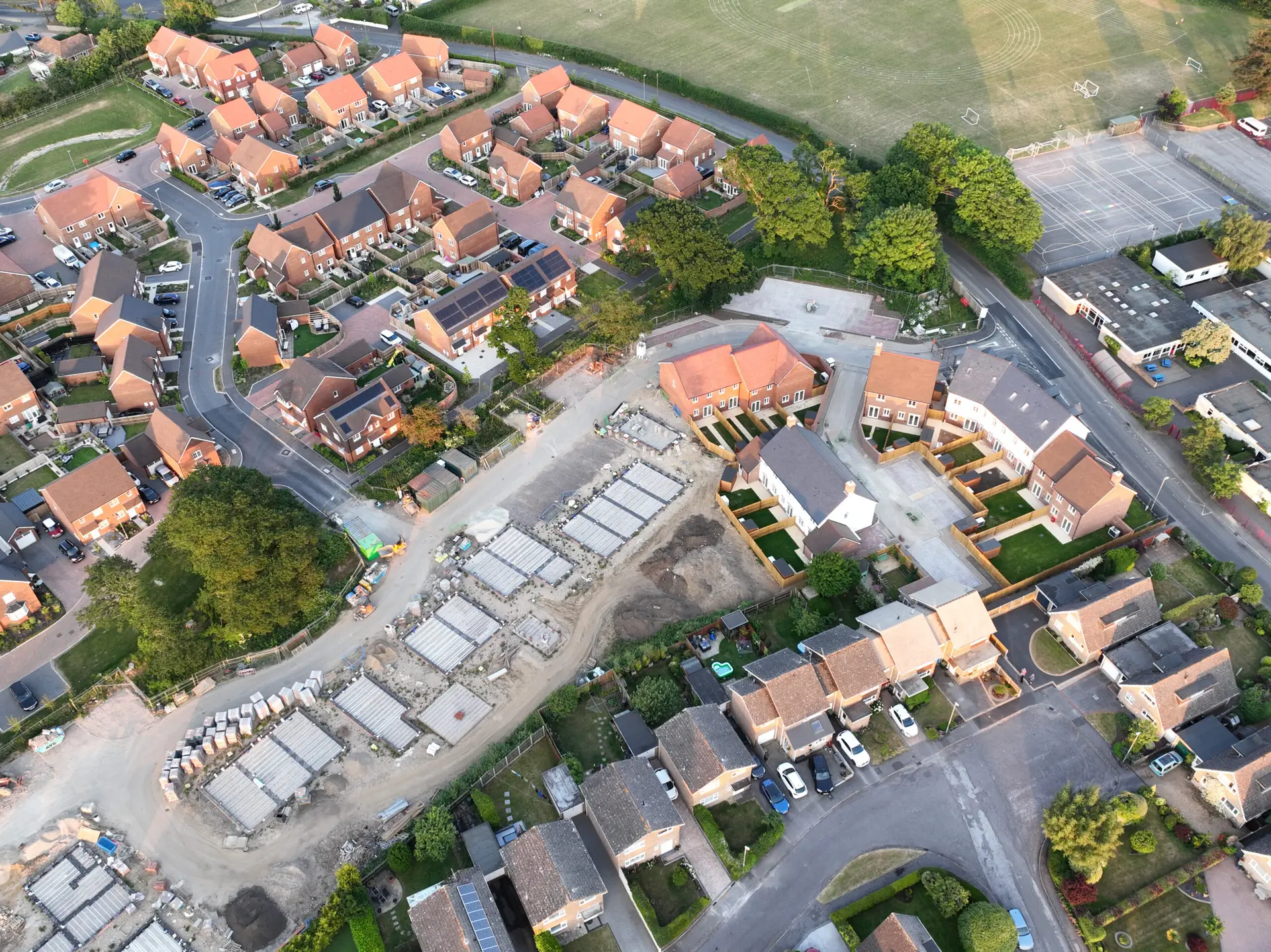 Aerial view looking on an area of new build housing construction on the edge of existing houses and green fields