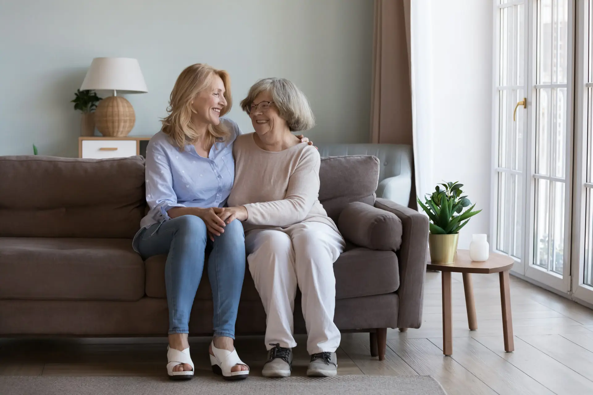 Happy mature grownup daughter visiting elderly mom, enjoying home