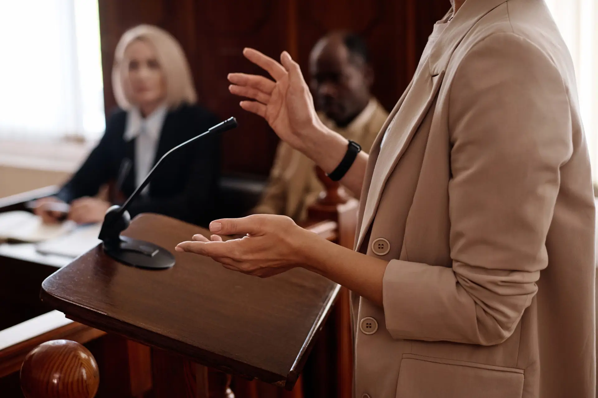 Cropped shot of young female witness in beige blazer standing by tribune