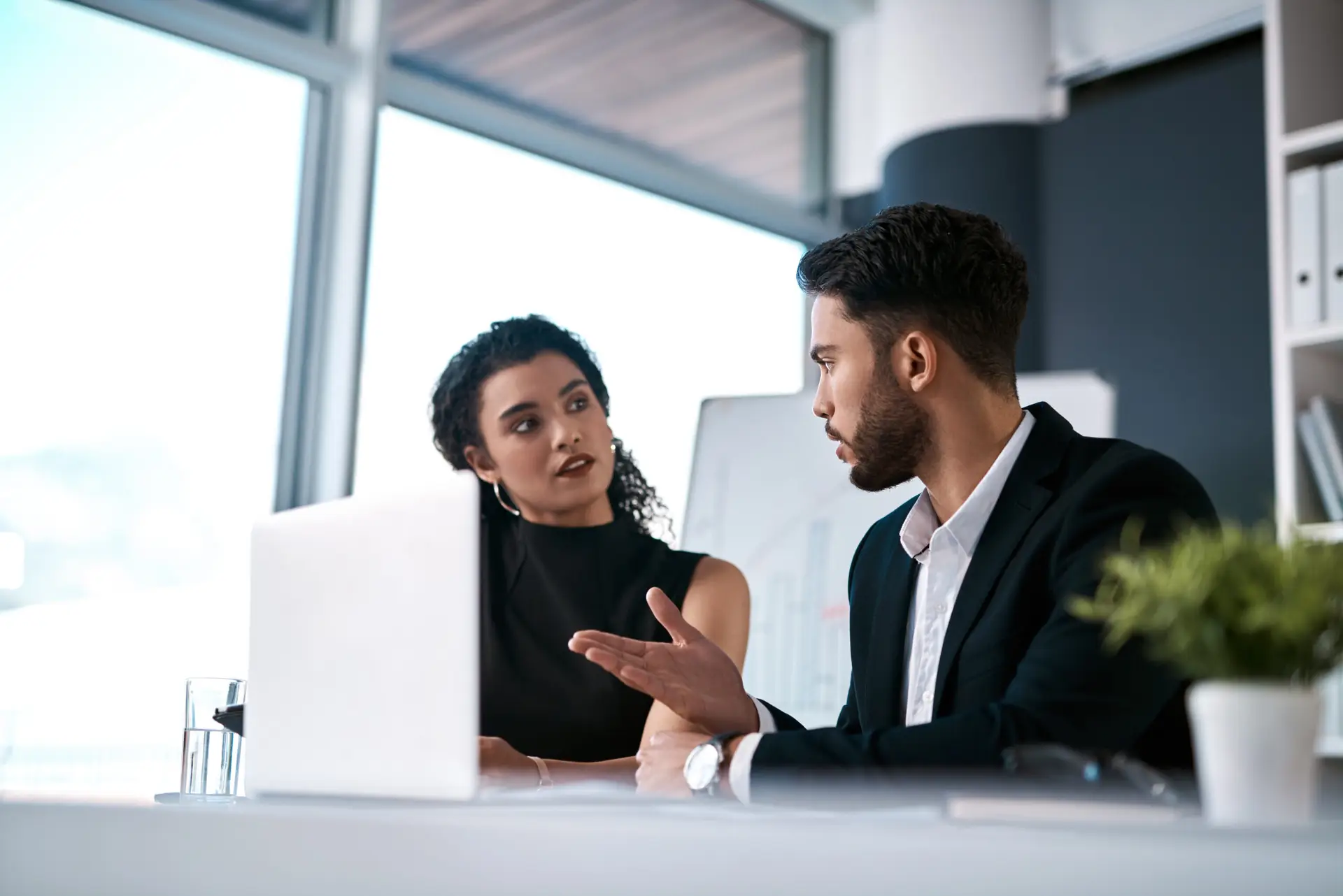 Serious, business meeting and people with laptop for performance review, communication and feedback. Corporate team, man and woman with computer in office for discussion and collaboration on project