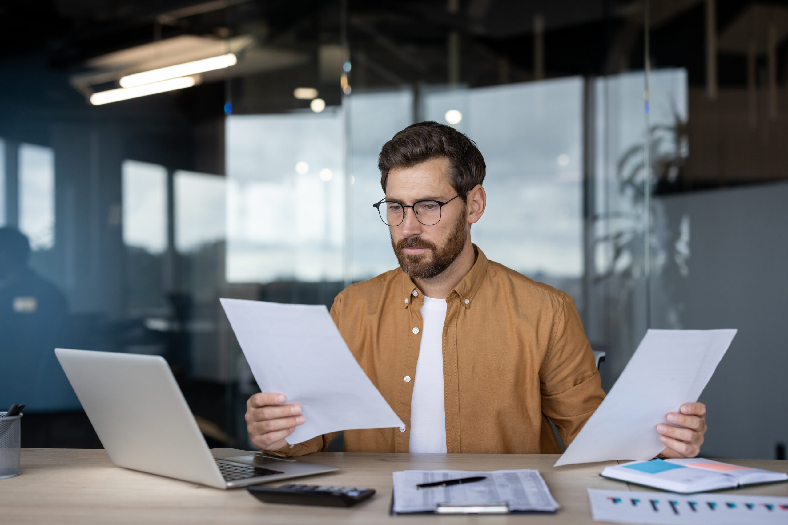 Professional businessman reading documents reviewing financial data in office