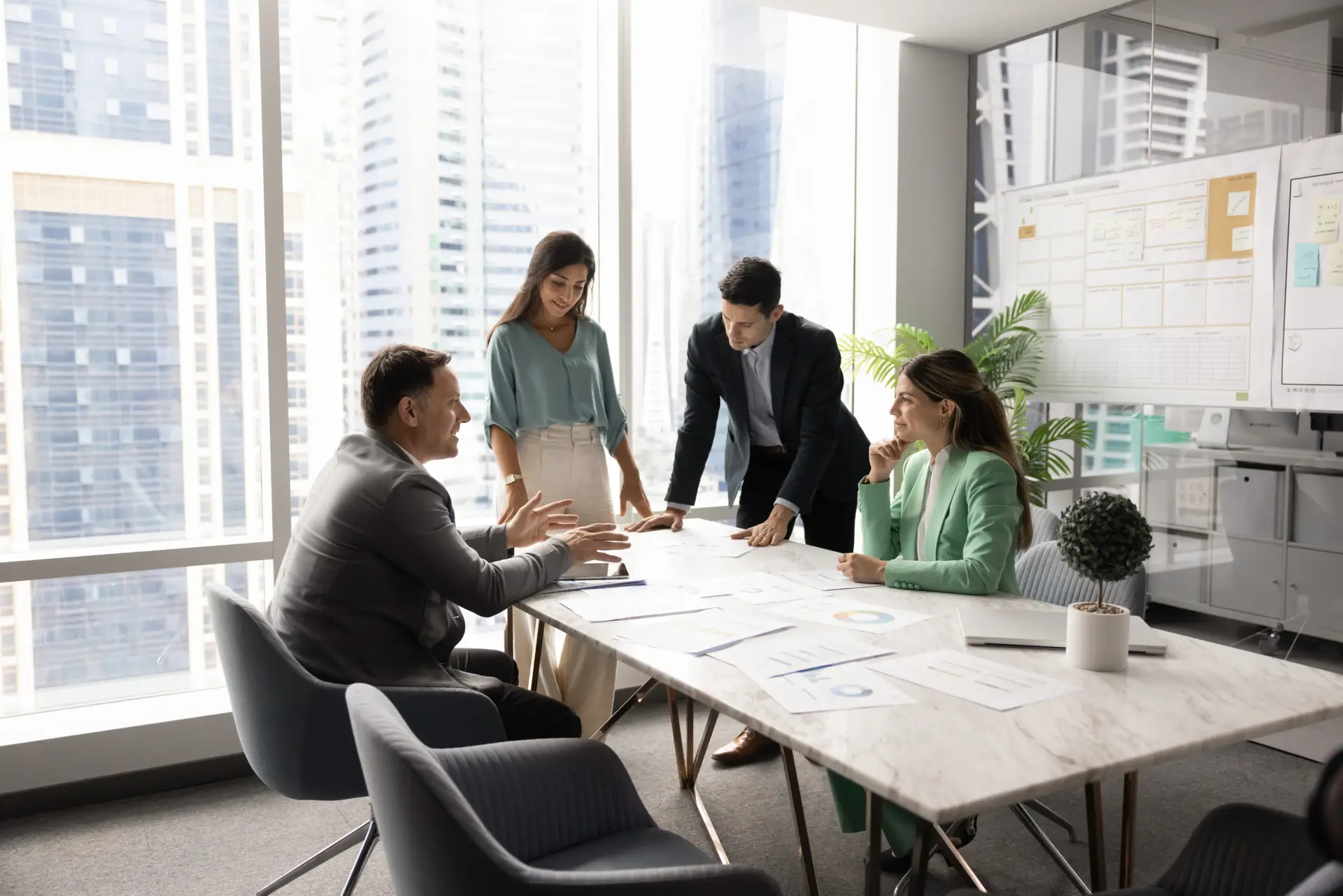 Multiethnic startup developers team gather around boardroom table brainstorming insights