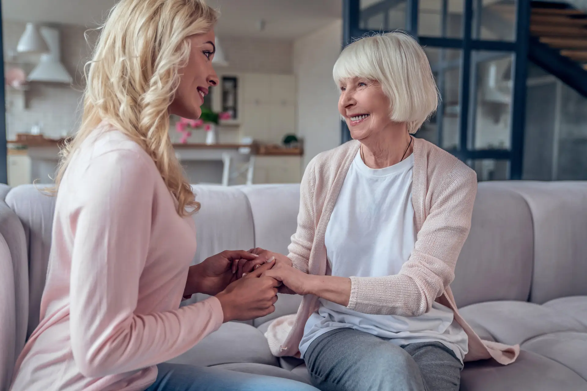 Senior woman and her attractive daughter spending time together at home and sitting on sofa. Happy Mothers' Day.