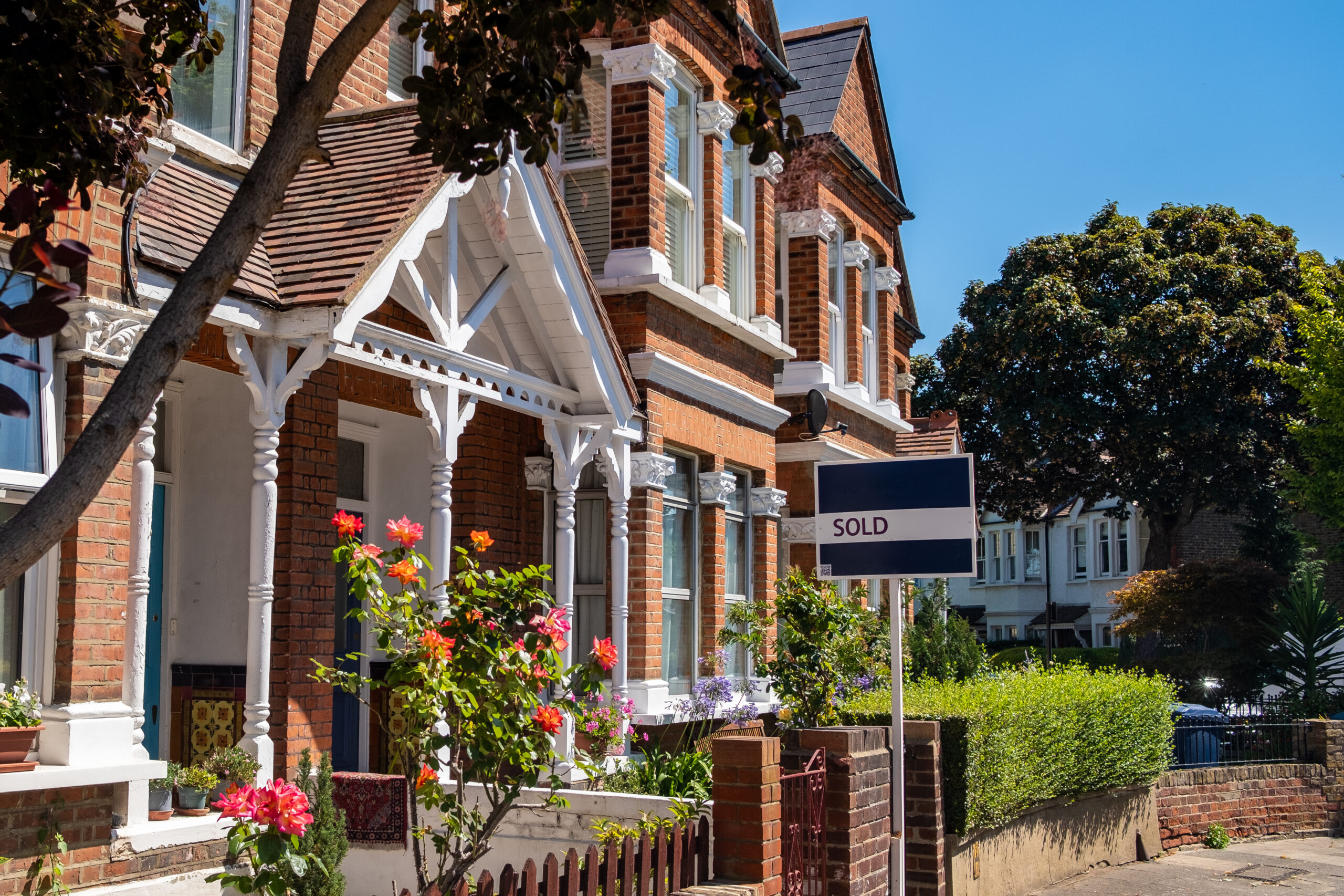 House Sold sign on attractive street of residential British houses