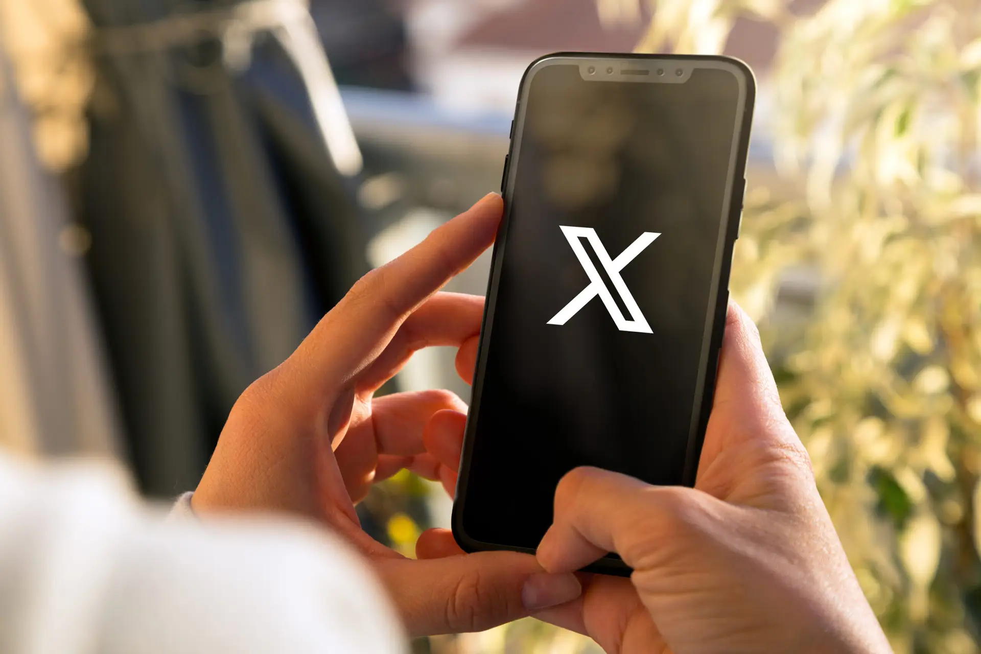 Woman holding her phone with the X social media logo on the screen. Former Twitter Social network.