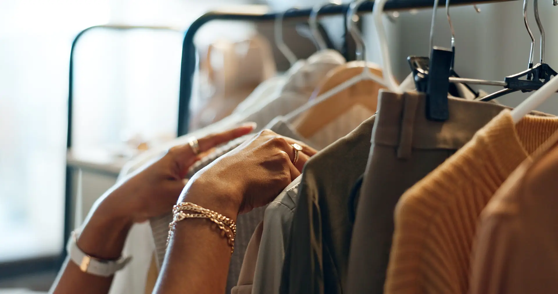 Hands of designer, clothes rail or choice in studio, workshop or small business for sample, show or collection. Creative woman, closeup or decision for design, fabric or clothing fashion in store